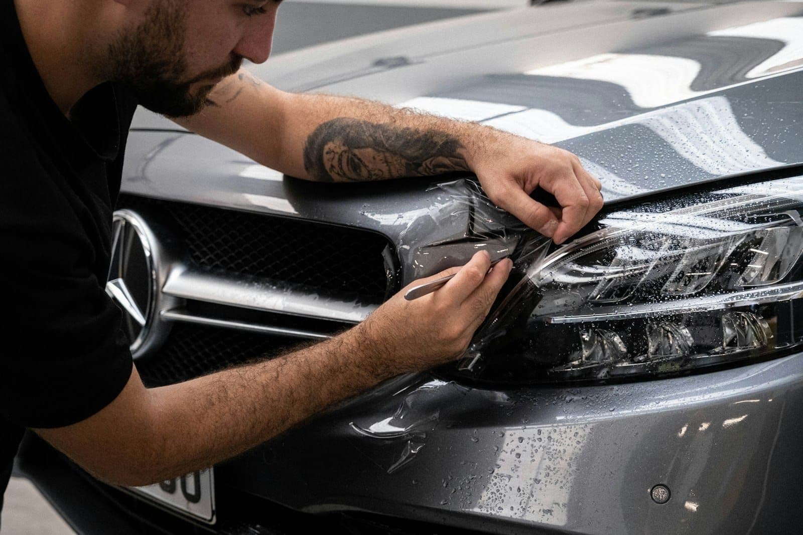 A certified applicator fitting paint protection film to a car